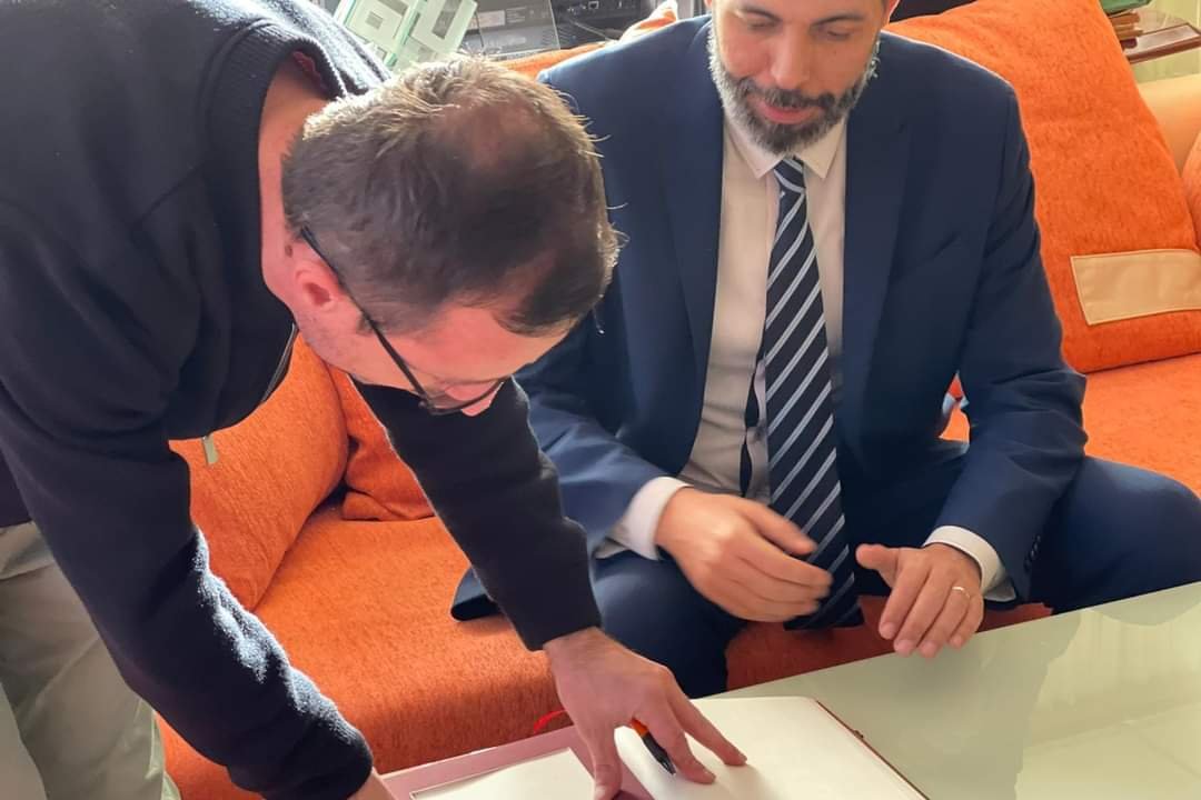 Deux hommes examinent un livret posé sur une table basse